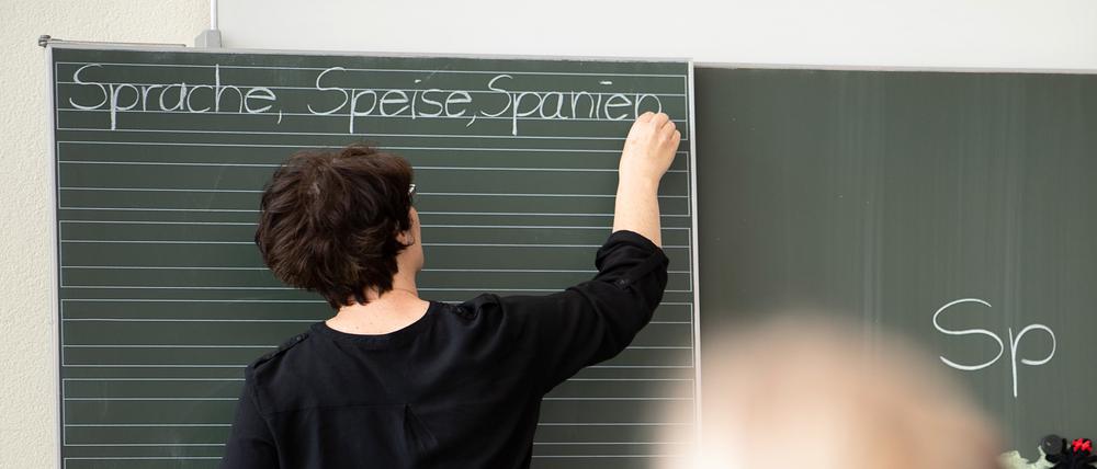 ARCHIV - 13.05.2019, Baden-Württemberg, Remshalden: Eine Lehrerin schreibt in einer Grundschule Worte an eine Tafel. In den Schulen gibt es nach Ansicht des Deutschen Lehrerverbands noch keine Entspannung der Corona-Lage. Foto: Sebastian Gollnow/dpa +++ dpa-Bildfunk +++
