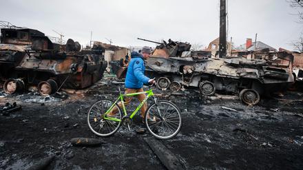 01.03.2022, Ukraine, Butscha: Ein Mann geht an den Überresten eines russischen Militärfahrzeugs in Bucha, nahe der ukrainischen Hauptstadt Kiew, vorbei. Russland hat am Dienstag den Beschuss von Charkiw, der zweitgrößten Stadt der Ukraine, verstärkt. Foto: Serhii Nuzhnenko/AP/dpa +++ dpa-Bildfunk +++