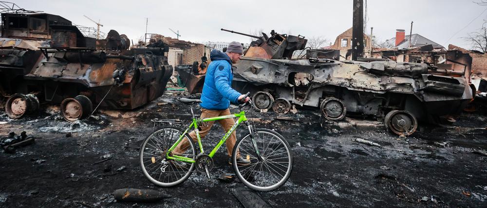 01.03.2022, Ukraine, Butscha: Ein Mann geht an den Überresten eines russischen Militärfahrzeugs in Bucha, nahe der ukrainischen Hauptstadt Kiew, vorbei. Russland hat am Dienstag den Beschuss von Charkiw, der zweitgrößten Stadt der Ukraine, verstärkt. Foto: Serhii Nuzhnenko/AP/dpa +++ dpa-Bildfunk +++