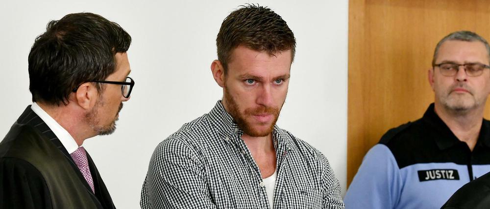 Der angeklagte frühere NPD-Politiker Maik Schneider (Mitte) wartet im Landgericht Potsdam auf den Prozessbeginn.