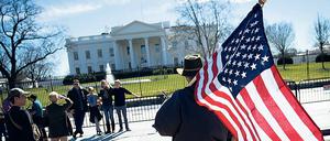 Ein Mann mit USA-Flagge vor dem Weißen Haus in Washington.