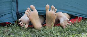 Two people's feet sticking out of tent door.