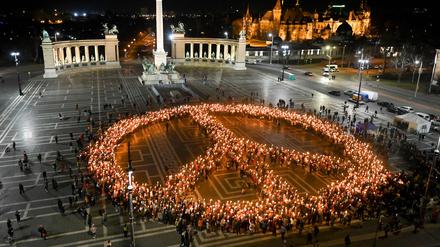 TOPSHOT - Protestors against the war and Russian invasion of Ukraine form the peace symbol during a demonstration at Heroes' Square in central Budapest, on March 9, 2022. (Photo by Attila KISBENEDEK / AFP)