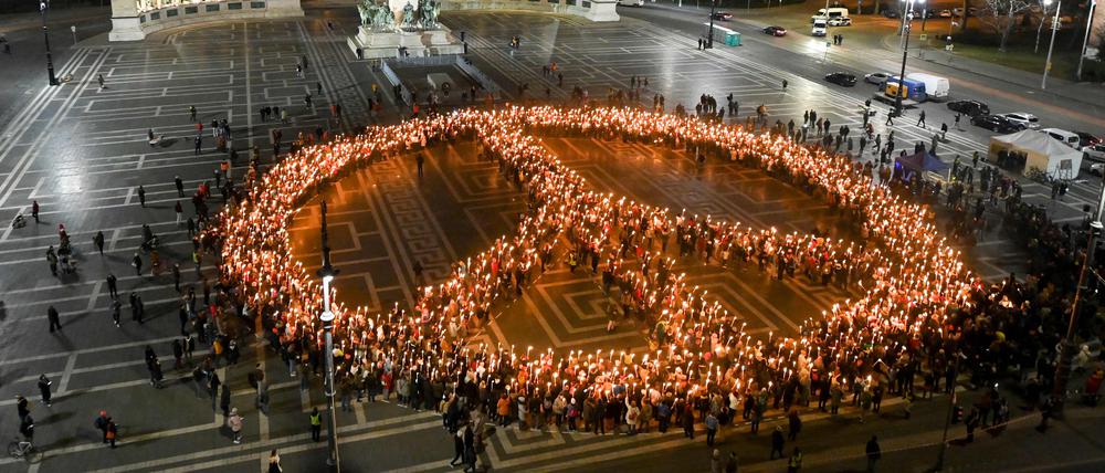 TOPSHOT - Protestors against the war and Russian invasion of Ukraine form the peace symbol during a demonstration at Heroes' Square in central Budapest, on March 9, 2022. (Photo by Attila KISBENEDEK / AFP)