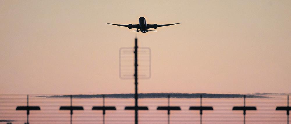 Ein Flugzeug startet vom Flughafen Berlin Brandenburg (BER) in den roten Abendhimmel.