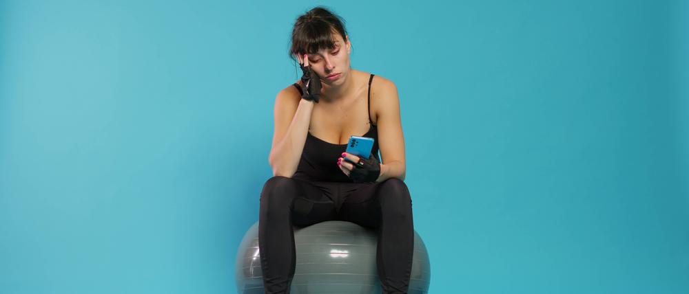 Active person yawning and using smartphone on break from workout.