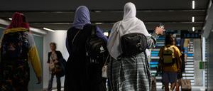 Frauen tragen Abayas, während sie durch eine Unterführung gehen. 