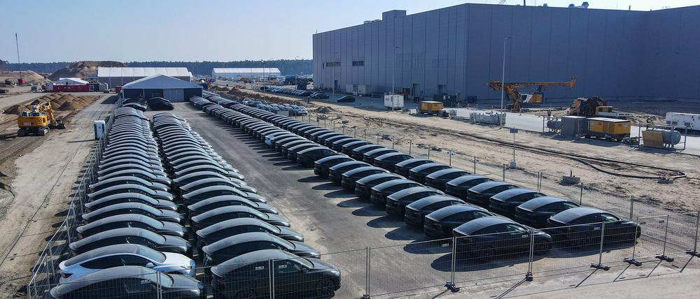 Der Parkplatz ist voll. Zahlreiche Fahrzeuge vom Typ Tesla Model Y stehen schon vor dem neuen Werk in Grünheide. Der US-Autohersteller durfte bereits vor der offiziellen Betriebserlaubnis Elektroautos zu Testzwecken produzieren.