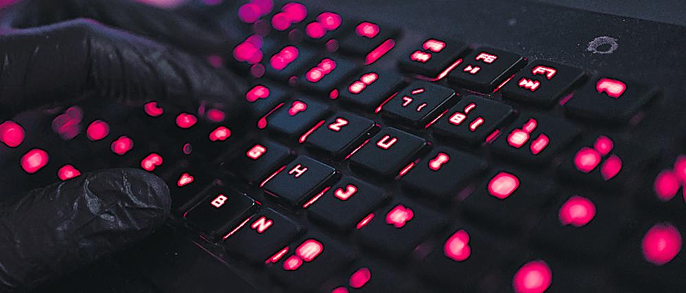 ILLUSTRATION - Ein Mann trägt Handschuhe und tippt auf einer Tastatur. Mehrere Bundestags- und Landtagsabgeordnete sind in den vergangenen Tagen das Ziel von Cyberangriffen geworden - vermutlich aus Russland. +++ dpa-Bildfunk +++