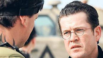 Rückendeckung. Verteidigungsminister Karl Theodor zu Guttenberg steht vor einem Soldaten in Kundus. Die Politik insgesamt stehe hinter den Soldaten, sagte der Minister. Foto: dpa