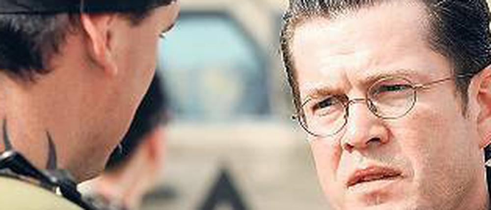 Rückendeckung. Verteidigungsminister Karl Theodor zu Guttenberg steht vor einem Soldaten in Kundus. Die Politik insgesamt stehe hinter den Soldaten, sagte der Minister. Foto: dpa