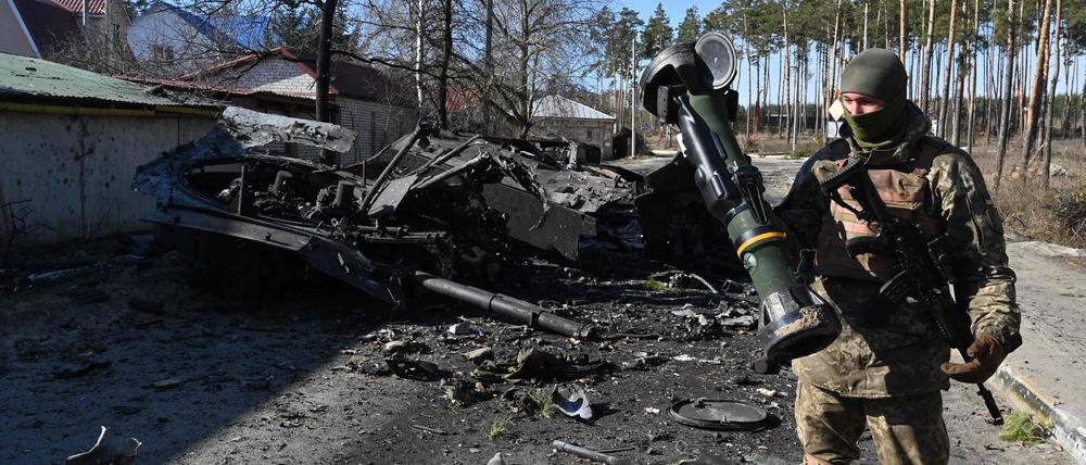 Ein ukrainischer Soldat steht mit einer Panzerabwehrwaffe vor einem mutmaßlich russischen Truppentransporter in Irpin.