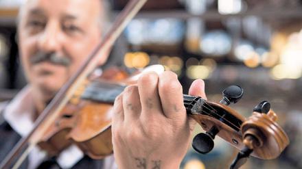Musikanten, überall. Dieser Herr erfreut die Kunden in der zentralen Markthalle mit seinen Geigenklängen. Foto: picture-alliance/lonely planet