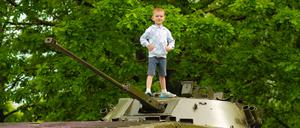 boy child explores old vintage military tank