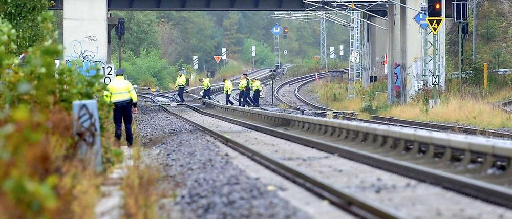 Polizeibeamte untersuchen in Berlin die Umgebung einer Bahnstrecke, an Brandsätze entdeckt wurden. Die Gleise sind nicht durch Zäune gesichert. 