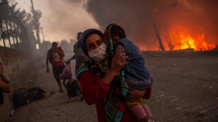Eine Frau schützt ihr Kind vor den Flammen in Moria.