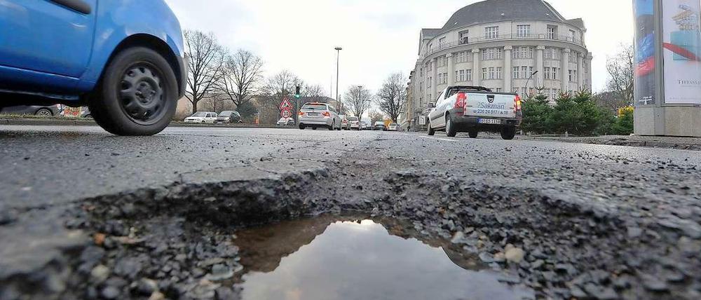 Ein Pkw fährt Mitte Dezember am Tempelhofer Damm an einem Schlagloch vorbei. Nach dem kürzlichen Wintereinbruch treten im gesamten Stadtgebiet verstärkt Straßenschäden auf, die durch Frost entstanden sind. 