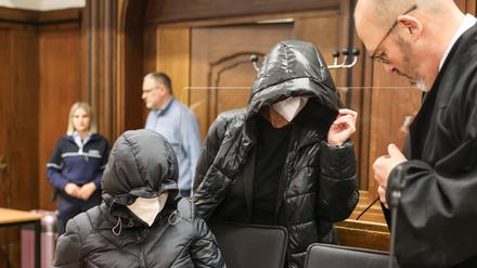 Die beiden Angeklagten kommen mit Kapuzen auf den Köpfen neben dem Anwalt Lutz Adam (r.) in den Verhandlungssaal. 