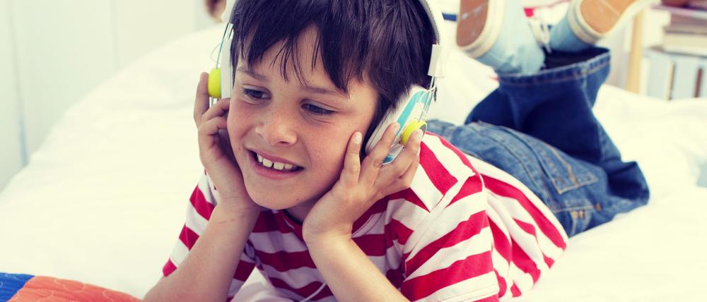 Mit Kopfhörern. Viele Kinder lieben es, sich mit einem Hörspiel in eine andere Welt zu versetzen.