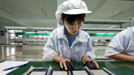 Eine Arbeiterin in China baut ein Ebook zusammen. Chinas Wirtschaft hat im dritten Quartal zugelegt.
