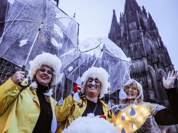 Besonders in Köln regnete es am Morgen heftig. Diese drei Karnevalistinnen haben ihre Kostüme gleich thematisch angepasst.