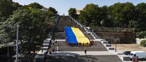 Kinder tragen eine ukrainische Flagge die berühmte Freitreppe am Hafen von Odessa hinauf.
