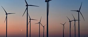 Farbenprächtig leuchtet der Morgenhimmel und die Mondsichel kurz vor Sonnenaufgang hinter Windenergieanlagen. (Symbolfoto)