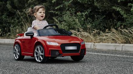 A girl riding a toy car