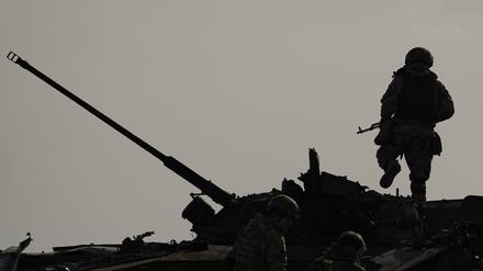 Ein ukrainischer Soldat springt von einem zerstörten russischen Kampffahrzeug in Butscha (Ukraine).