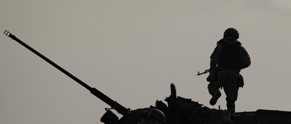Ein ukrainischer Soldat springt von einem zerstörten russischen Kampffahrzeug in Butscha (Ukraine).