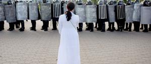 Eine Demonstrantin steht in Minsk Sicherheitskräften gegenüber. 