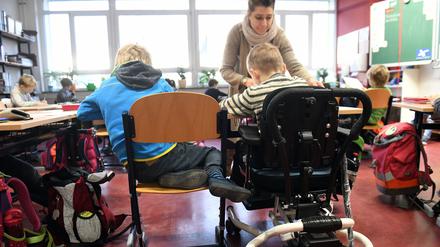 Eine Schulbegleiterin unterstützt ein Kind im Unterricht.