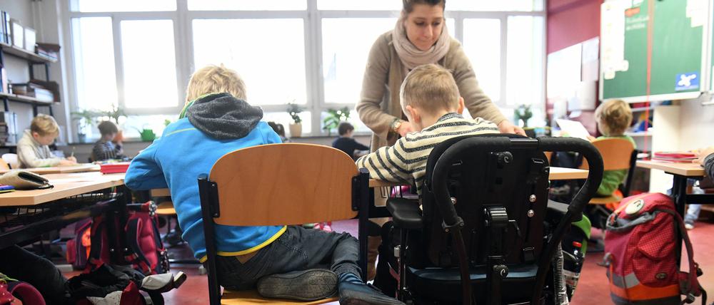 Eine Schulbegleiterin unterstützt ein Kind im Unterricht.