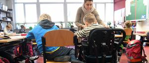 Eine Schulbegleiterin unterstützt ein Kind im Unterricht.