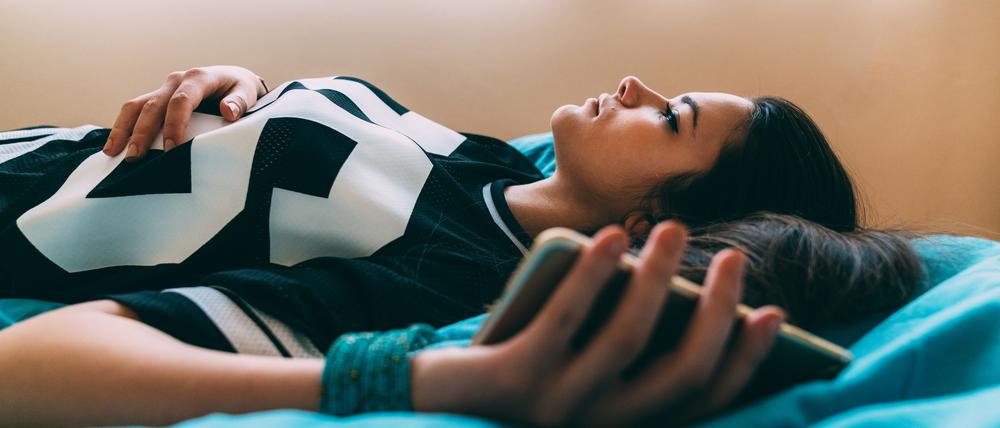 Young woman feeling worried after checking COVID-19 symptoms online and staying home for safety
