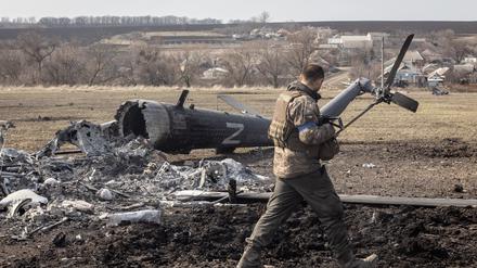 Ein ukrainischer Soldat betrachtet einen abgeschossenen russischen Militärhelikopter in Mala Rohan nahe Charkiw.