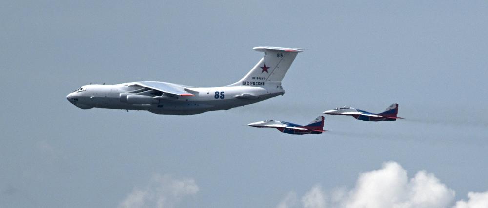 Ein russisches Militärtransportflugzeug vom Typ Il-80, bekannt als „Weltuntergangsflugzeug“, wird von zwei MiG-29-Kampfjets begleitet.