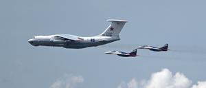Ein russisches Militärtransportflugzeug vom Typ Il-80, bekannt als „Weltuntergangsflugzeug“, wird von zwei MiG-29-Kampfjets begleitet.