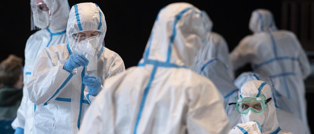 Mitarbeiter in einem Mainzer Corona-Testzentrum tragen Schutzanzüge.