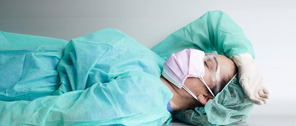 Tired female doctor wearing protective workwear resting on bench in hospital model released Symbolfoto property released JCMF00884 
