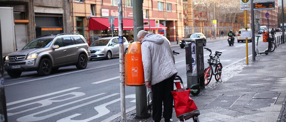 Ein Flaschensammler blickt am 18.12.2019 in einen Mülleimer auf der Kochstraße. Foto: Wolfram Steinberg/dpa