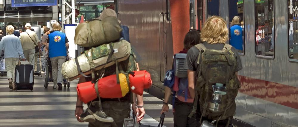 Jugendliche Rucksacktouristen neben einem Zug auf einem Bahnsteig auf dem Hauptbahnhof von Frankfurt am Main.