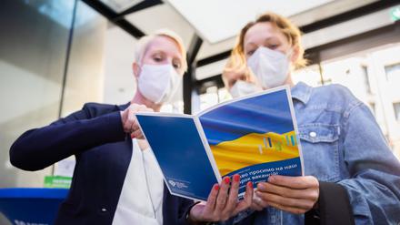Eine Besucherin (r.) lässt sich bei der Jobmesse für ukrainische Geflüchtete von der IHK Berlin und der Agentur für Arbeit den Messeplan zeigen. 