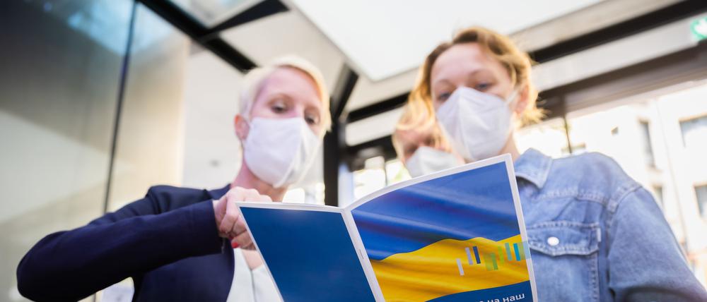 Eine Besucherin (r.) lässt sich bei der Jobmesse für ukrainische Geflüchtete von der IHK Berlin und der Agentur für Arbeit den Messeplan zeigen. 