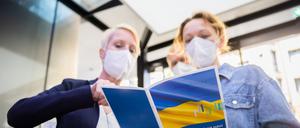 Eine Besucherin (r.) lässt sich bei der Jobmesse für ukrainische Geflüchtete von der IHK Berlin und der Agentur für Arbeit den Messeplan zeigen. 