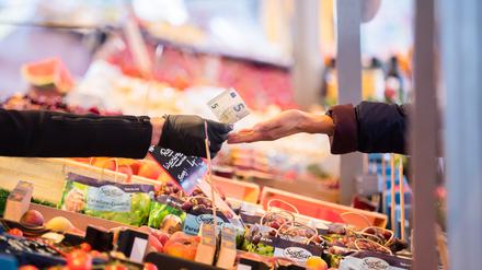 Geld wird auf einem Wochenmarkt im Berliner Ortsteil Schöneberg über eine Obst- und Gemüsetheke gereicht. Die Inflation in Berlin und Brandenburg steigt über acht Prozent laut dem Amt für Statistik Berlin-Brandenburg. +++ dpa-Bildfunk +++