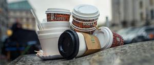 Einweg-Kaffeebecher und Plastikschalen stapeln sich an einem Gehweg in Berlin. 