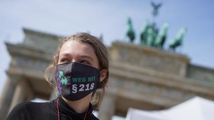 19.09.2020, Berlin: Eine Teilnehmerin der Demonstration «Marsch für das Leben» gegen Abtreibungen vom "Bündnis für sexuelle Selbstbestimmung, sexuelle Vielfalt und bunte Lebensentwürfe" trägt vor dem Brandenburger Tor eine Mund-Nasen-Bedeckung mit der Aufschrift "Weg mit §218". Foto: Jörg Carstensen/dpa +++ dpa-Bildfunk +++ | Verwendung weltweit