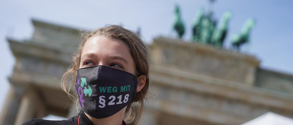 19.09.2020, Berlin: Eine Teilnehmerin der Demonstration «Marsch für das Leben» gegen Abtreibungen vom "Bündnis für sexuelle Selbstbestimmung, sexuelle Vielfalt und bunte Lebensentwürfe" trägt vor dem Brandenburger Tor eine Mund-Nasen-Bedeckung mit der Aufschrift "Weg mit §218". Foto: Jörg Carstensen/dpa +++ dpa-Bildfunk +++ | Verwendung weltweit