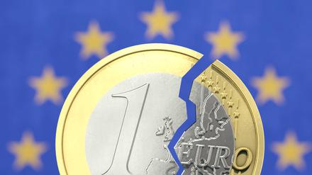 Gespaltene Euromünze vor EU-Flagge Symbolbild zum Thema Inflation in der EU / Eurokrise *** Split euro coin in front of EU flag symbol image about inflation in EU euro crisis 